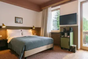 Chambre mit Balkon im HENRI Garmisch-Partenkirchen Ein Bett in einem Schlafzimmer mit stilvollem Interieur.