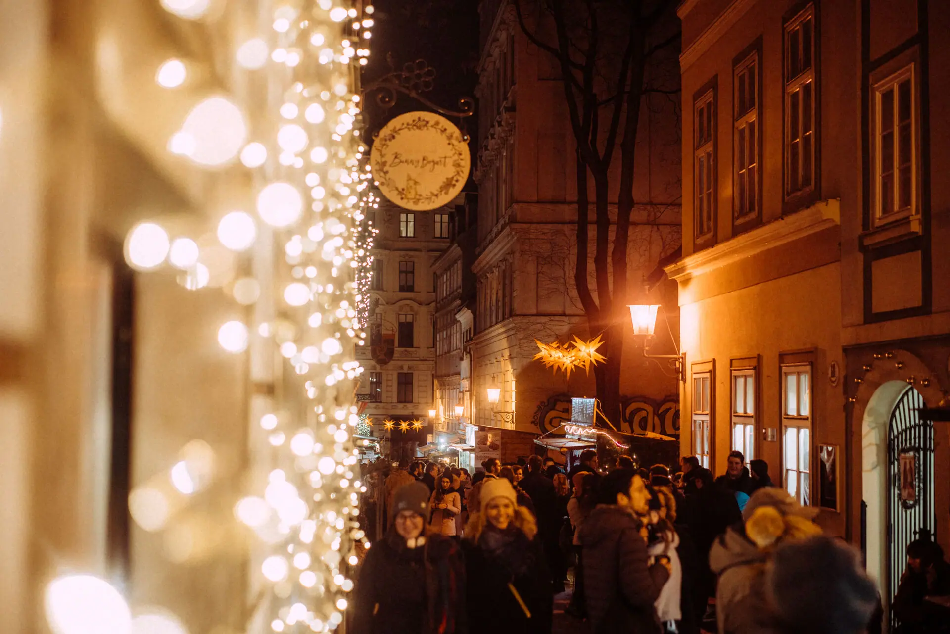 Weihnachtsbeleuchtung Eine Menschenmenge geht eine von Weihnachtslichtern beleuchtete Straße entlang.