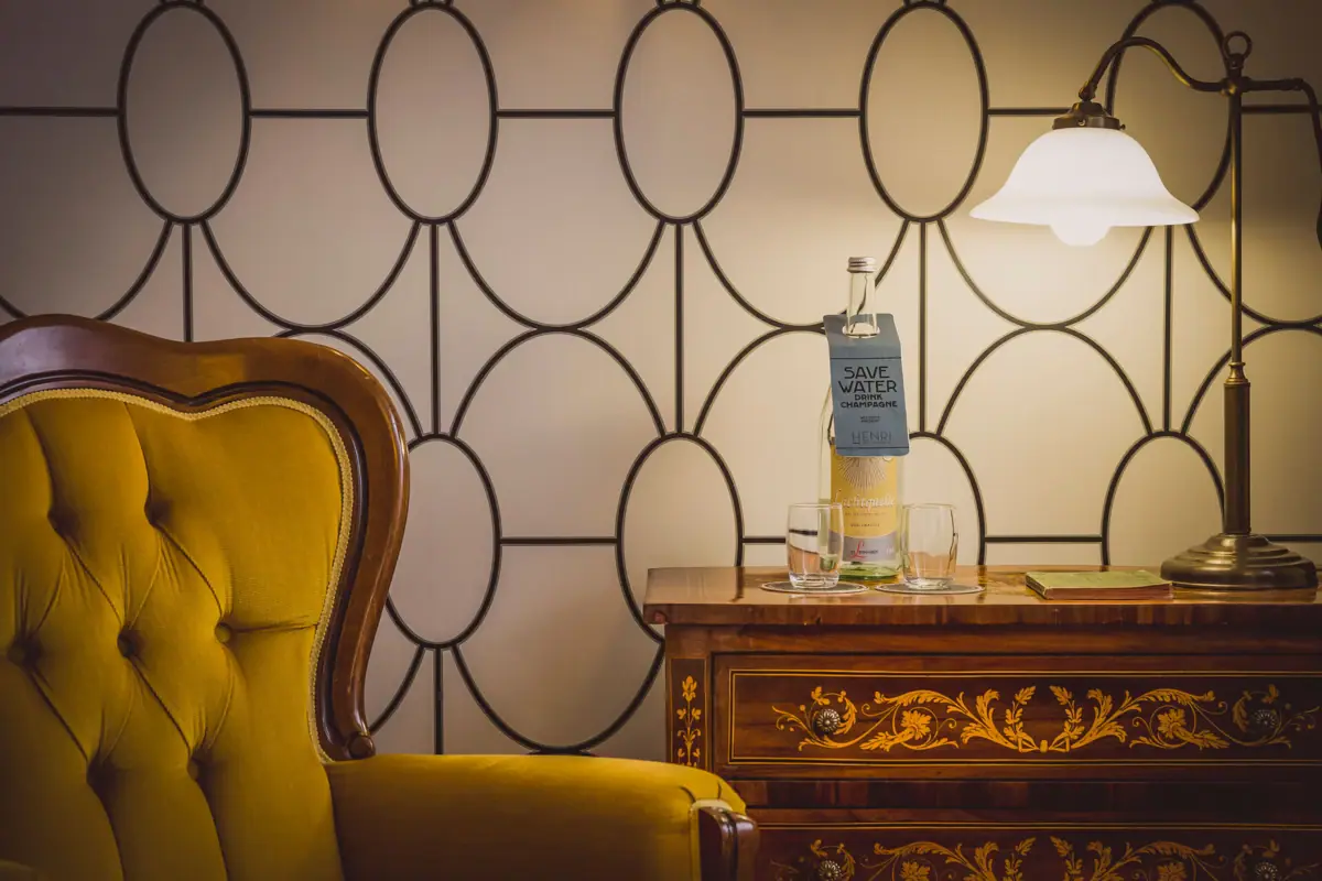 Ein Stuhl und ein Tisch mit Gläsern und einer Flasche darauf.