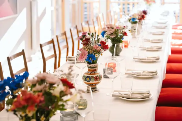 Langer Tisch mit Blumenarrangement und Weingläsern.