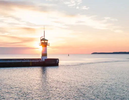Ein Leuchtturm auf einem Steg mitten im Ozean.