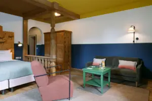 HENRI GAP Salon mit Balkon Ein Zimmer mit zwei Betten und einem grünen Tisch.