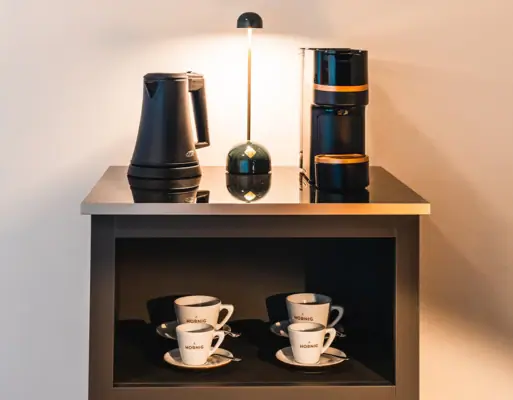 Kaffeemaschine, Wasserkocher und Tassen auf einem Regal