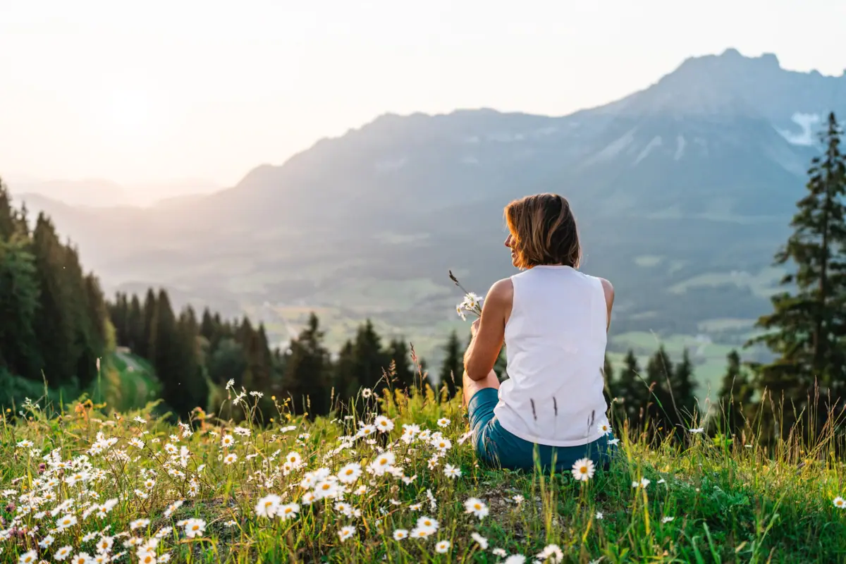 Blick auf die Berge Eine Frau sitzt auf einer Sommerwiese und schaut auf die Berge