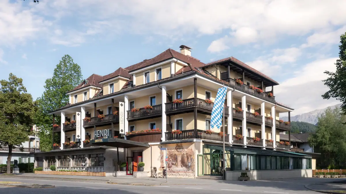 HENRI Garmisch-Partenkirchen Ein Gebäude mit vielen Balkonen vor einem bewölkten Himmel.