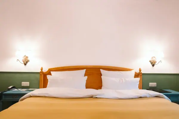 Hotelzimmer HENRI Hotel Garmisch-Partenkirchen Ein Bett mit weißen Kissen und Lampen an der Wand in einem Hotelzimmer im HENRI Hotel Garmisch-Partenkirchen.