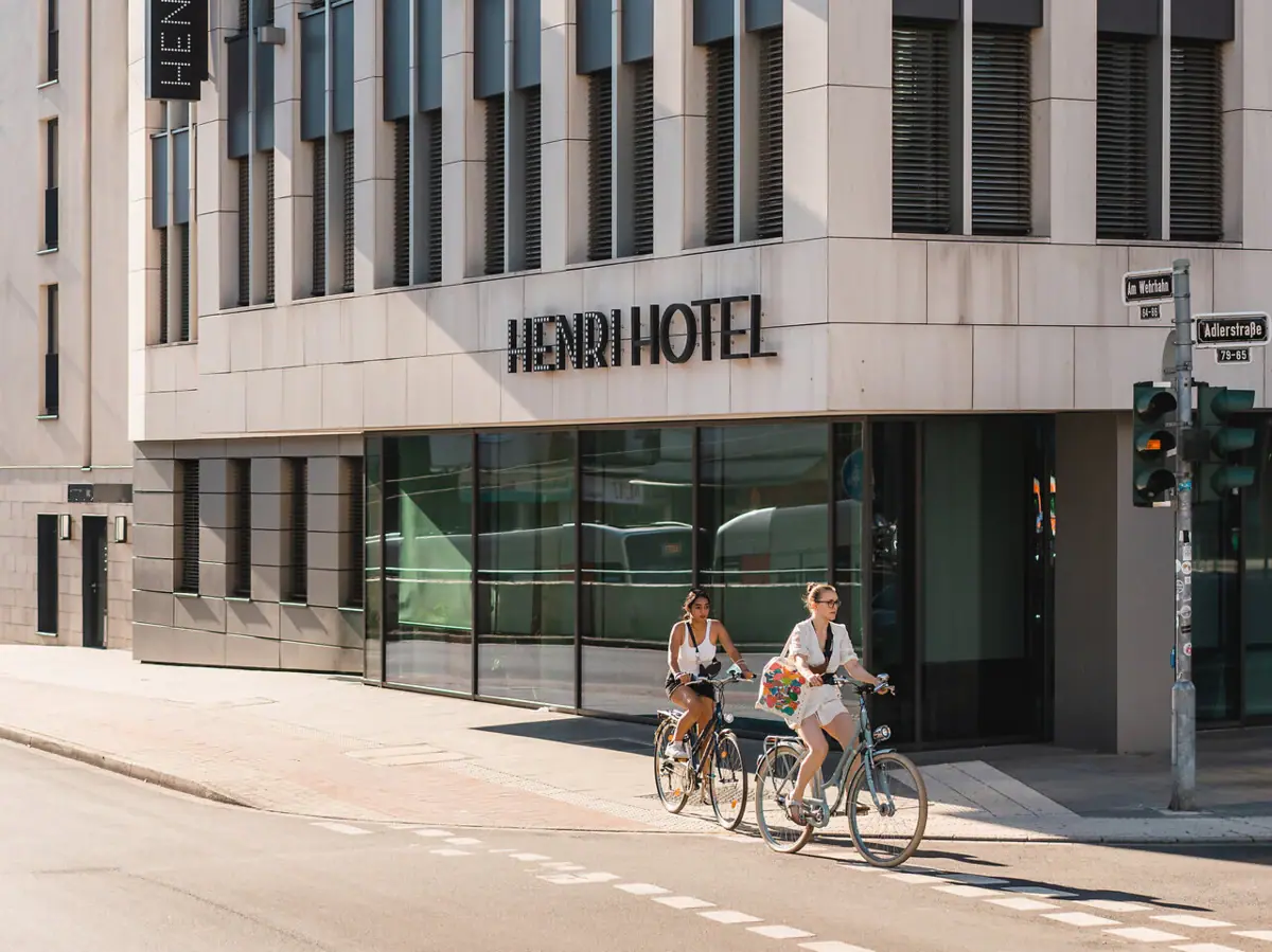 Eine Gruppe von Menschen fährt mit Fahrrädern vor einem Hotel.