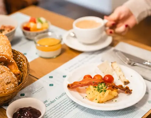 Eine Person hält eine Tasse Kaffee und einen Teller mit Essen.