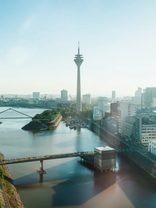 Ein Fluss mit einer Brücke und einer Stadt mit einem Turm.