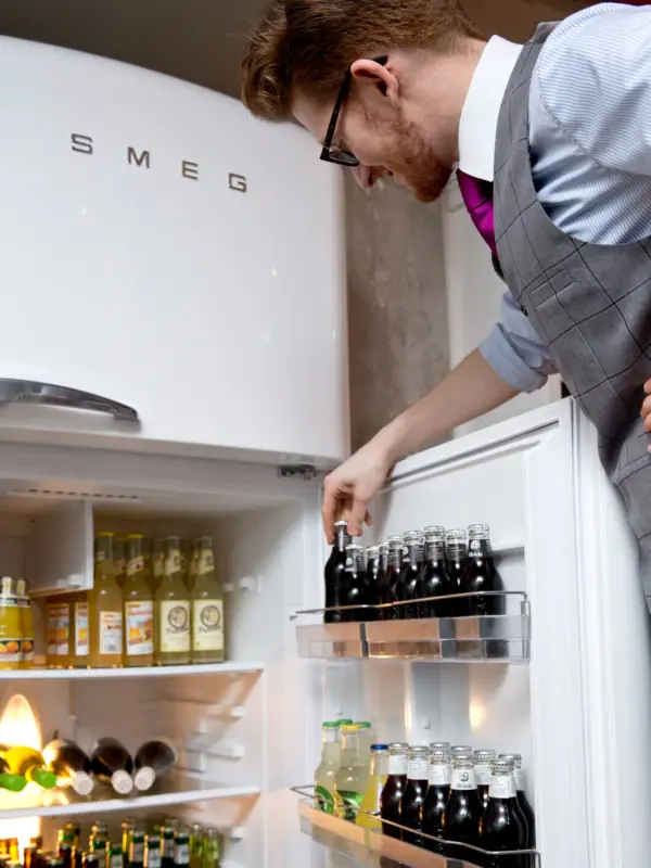 Ein Mitarbeiter schaut in den Getränkekühlschrank