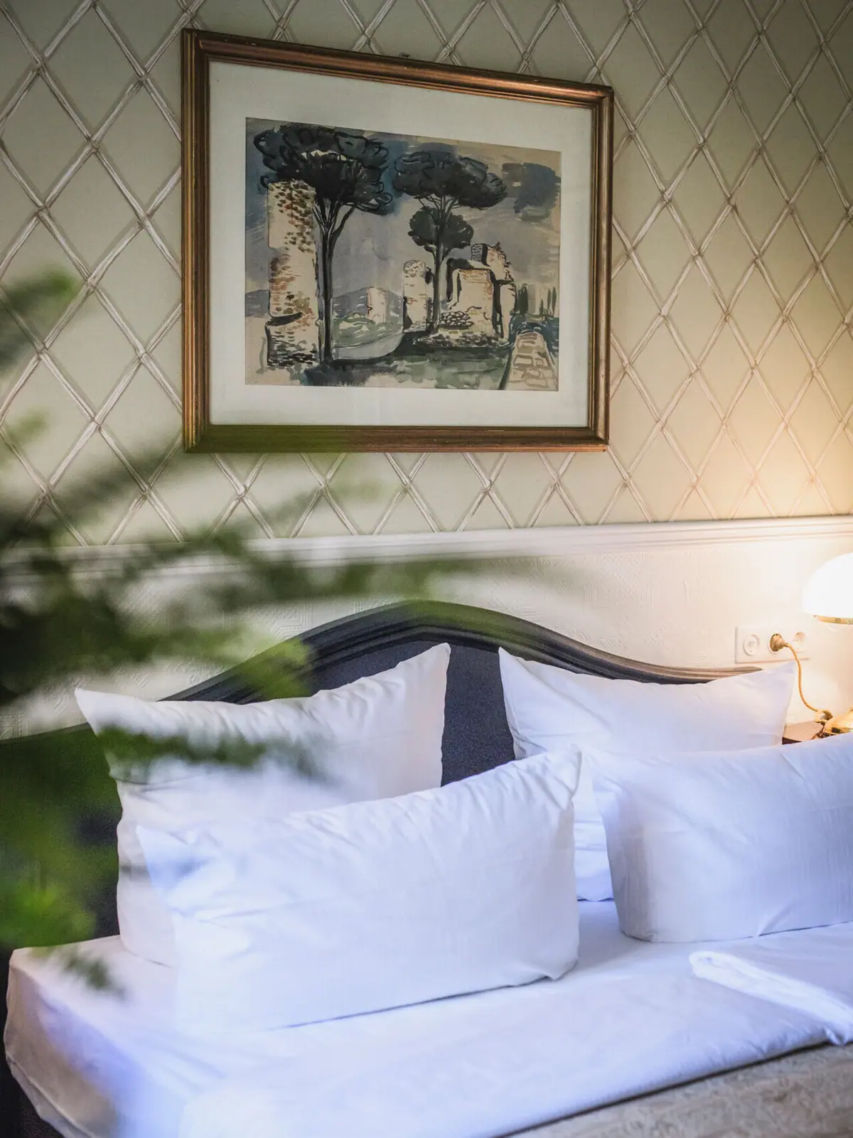 Bett mit 2 Kissen vor einer antiken Tapete