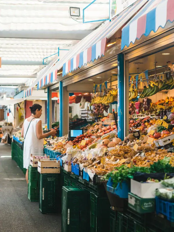 Frau steht vor einem Obststand auf einem Markt.