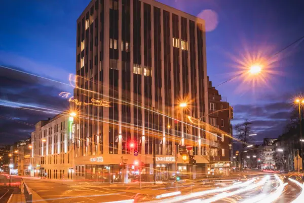 HENRI Düsseldorf Straße mit eingeschalteten Straßenlaternen und einem Gebäude im Hintergrund bei Nacht