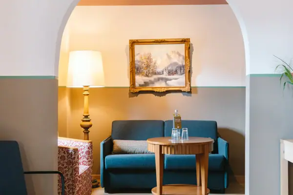 Hotelzimmer im HENRI Hotel Garmisch-Partenkirchen mit Sofa und Tisch.