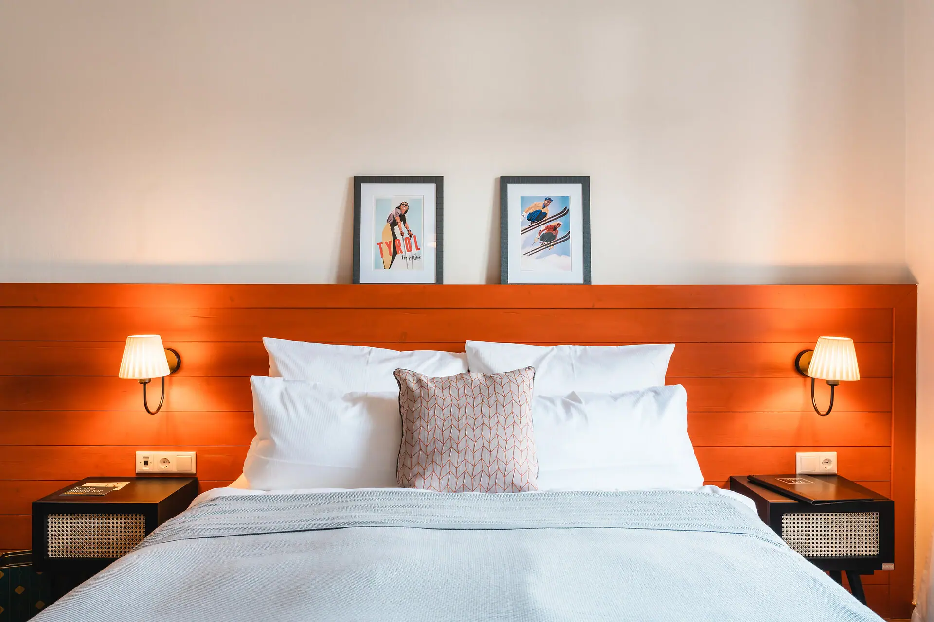 HENRI Kitzbühel Hotelzimmer Ein Bett mit einem Holzkopfteil und Lampen.