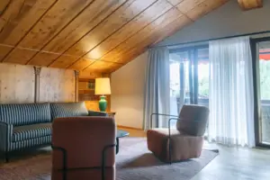 Sitzbereich Zimmer mit Holzdecke, Couch und Sesseln.