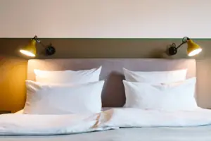 Ein Bett mit weißen Kissen und einer Lampe im HENRI Hotel Garmisch-Partenkirchen.