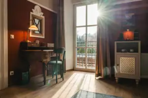 Das Hotelzimmer Salon im HENRI Hotel Kitzbühel mit roten Wänden, einem Schreibtisch und einem Fenster.