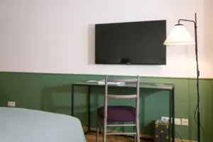 Fernseher und Schreibtisch im HENRI Garmisch-Partenkirchen Fernseher an der Wand im Hotelzimmer