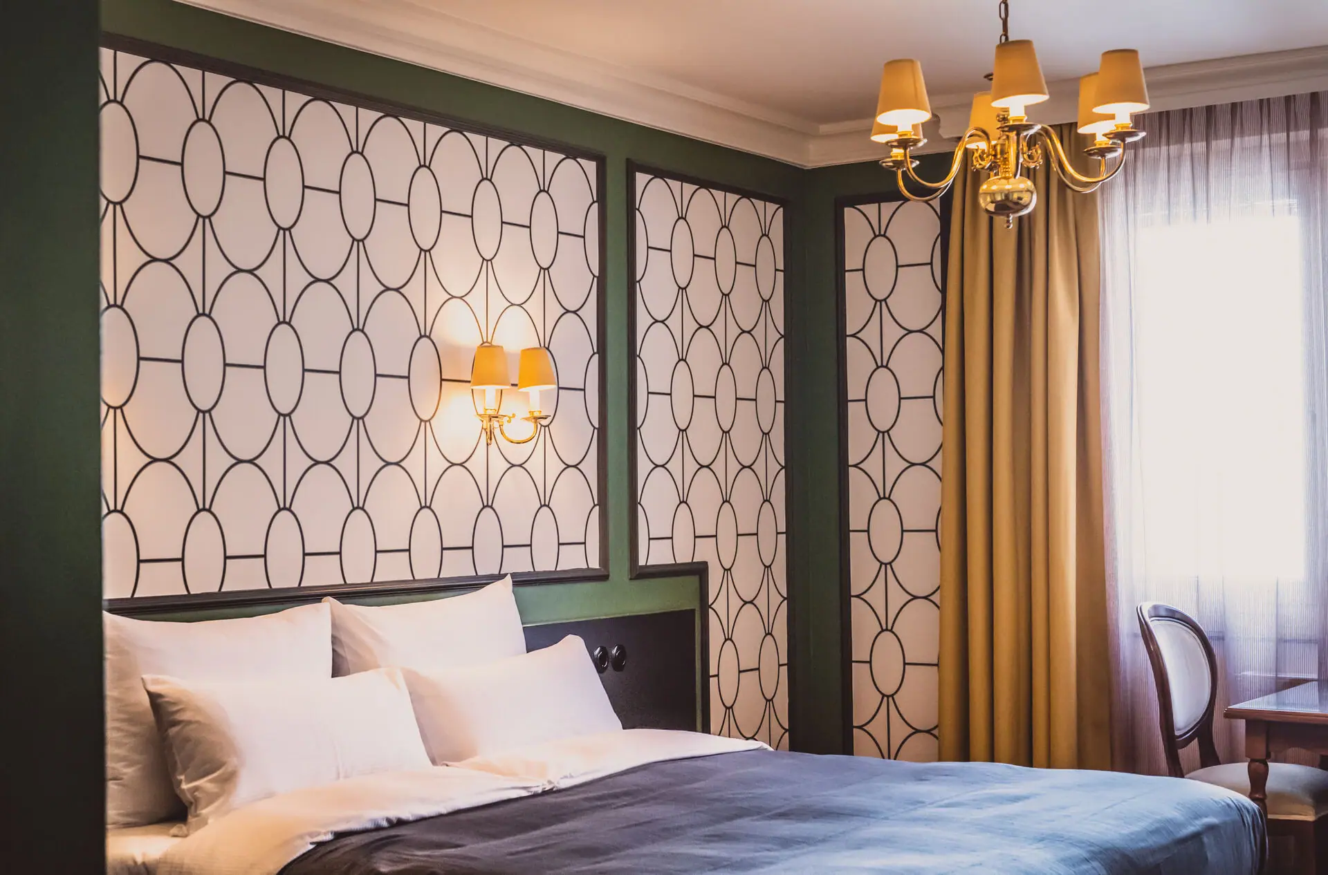 Zimmer Ein Bett mit einem Kronleuchter und Vorhängen.