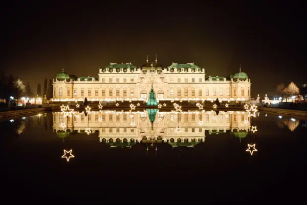 Ein beleuchtetes Gebäude bei Nacht mit Spiegelung im Wasser.