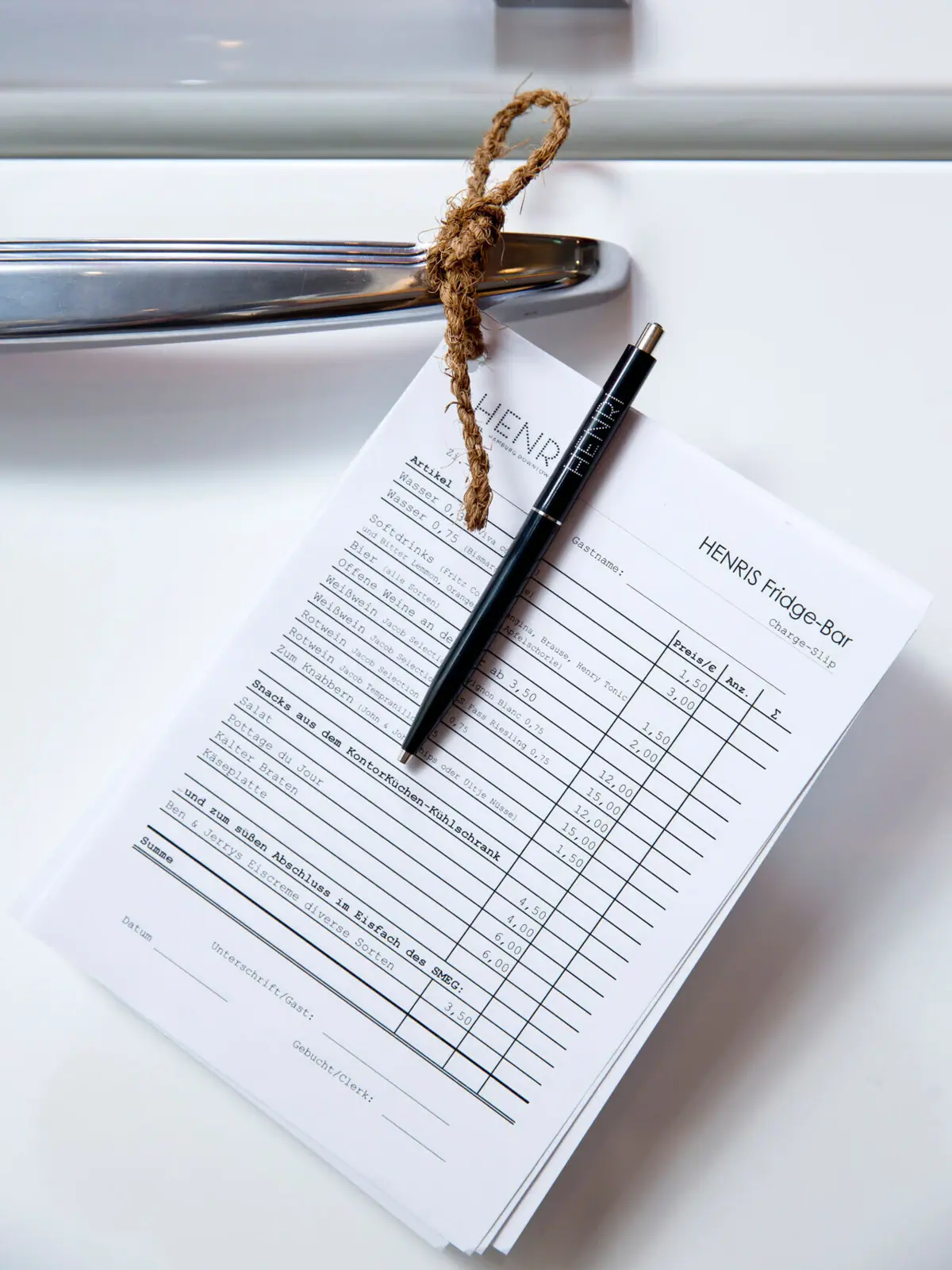 Ein Stift auf einem Blatt Papier hängt an einer Kühlschranktür.