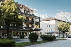 Außenansicht HENRI Hotel Garmisch-Partenkirchen mit Bäumen und einer Straße.
