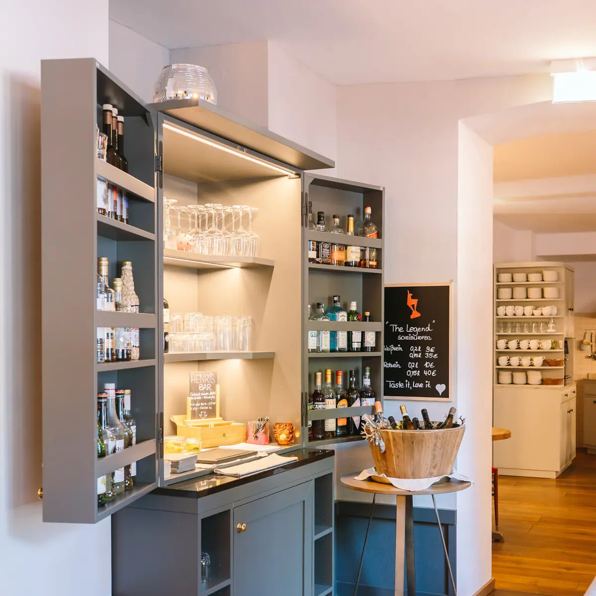 Ein Raum mit einem Schrank und Regalen mit Flaschen und Gläsern.