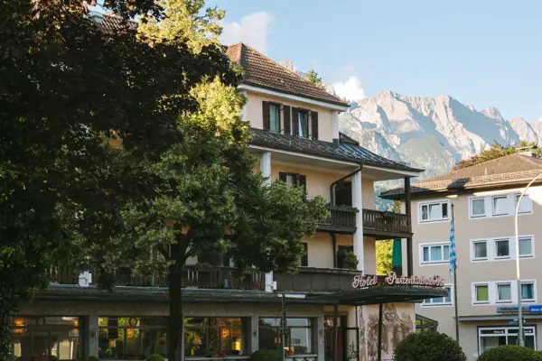 Ein Gebäude mit Bäumen und Bergen im Hintergrund.