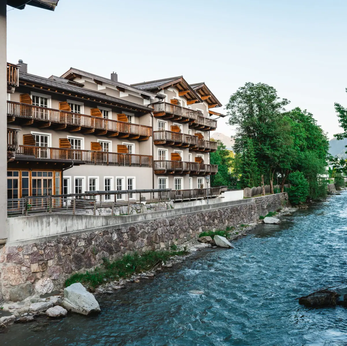 HERNI Kitzbühel Ein Fluss mit einem Gebäude und Bäumen.