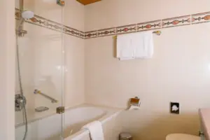 Badezimmer im HENRI Garmisch-Partenkirchen Badezimmer mit Glastür an der Dusche und modernen Armaturen.