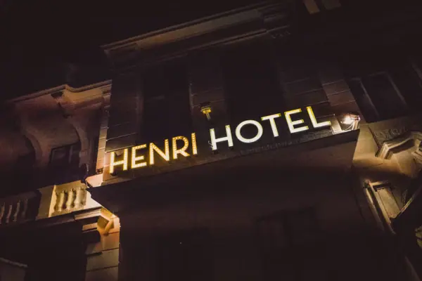 HENRI Hotel Berlin Fassade Leuchtschrift Nacht Die goldgelb leuchtende „HENRI HOTEL“ Neonschrift an der historischen Außenfassade des Hotels in Berlin bei Nacht.