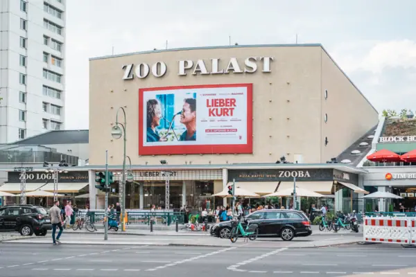 Die markante Fassade des historischen Zoo Palast Kinos in Berlin bei Tag mit aktueller Filmwerbung und Stadtverkehr im Vordergrund