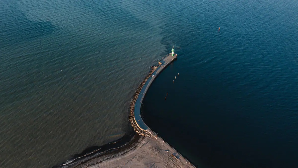 Nordermole Ein langer Pier in Travemünde mit einem Leuchtturm darauf.