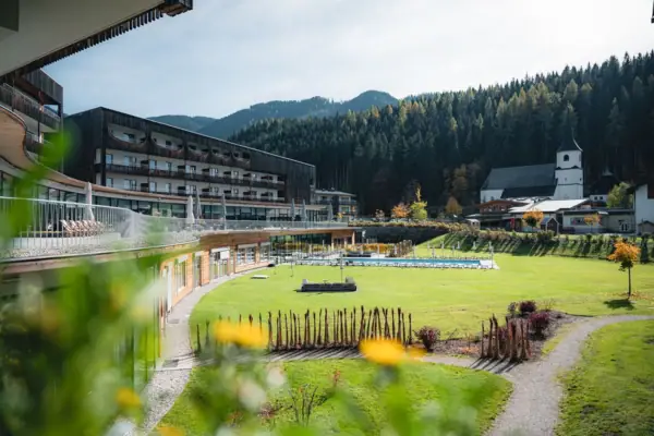 Grüne Rasenfläche mit dem aja Bergresort Werfenweng im Hintergrund.