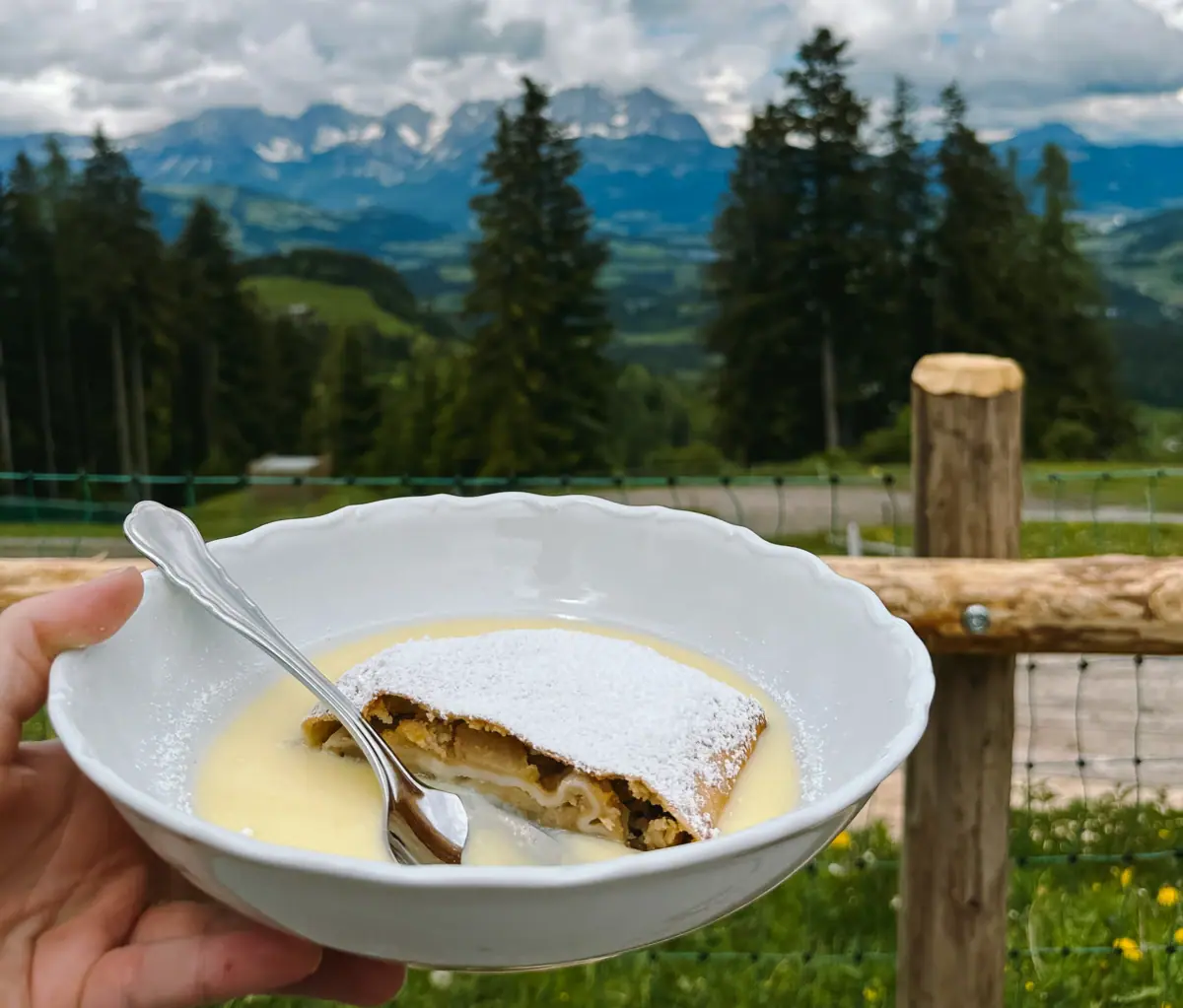 Eine Hand hält eine Schüssel mit Essen und einem Löffel.