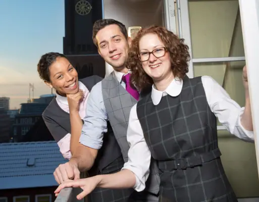 Eine Gruppe von Menschen steht vor einem Fenster.