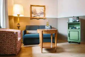 Hotelzimmer HENRI Hotel Garmisch-Partenkirchen Ein Wohnbereich mit Sofa, Sessel und Tisch in einem Hotelzimmer im HENRI Hotel Garmisch-Partenkirchen.