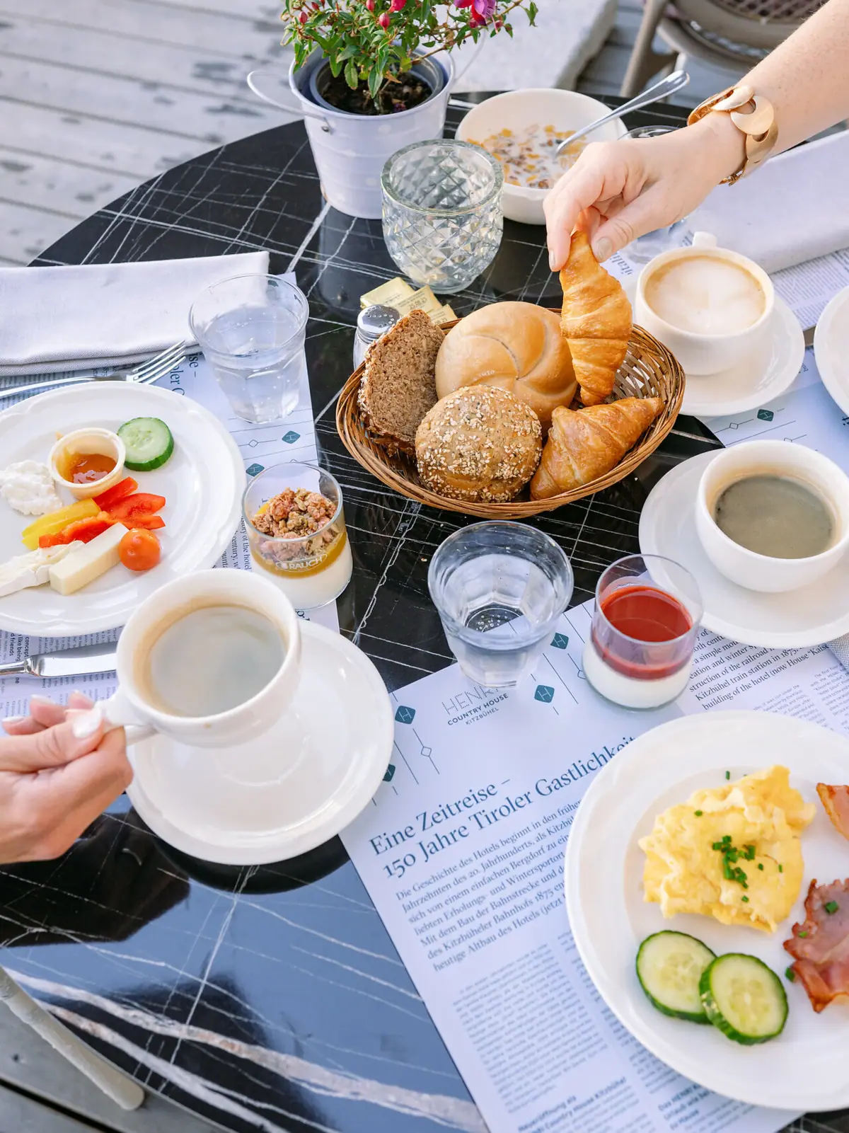 Eine Person hält ein Croissant und eine Schüssel mit Essen auf einem Tisch.