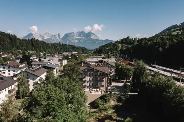 Das HENRI Hotel Kitzbühel mit Bäumen und Bergen im Hintergrund.