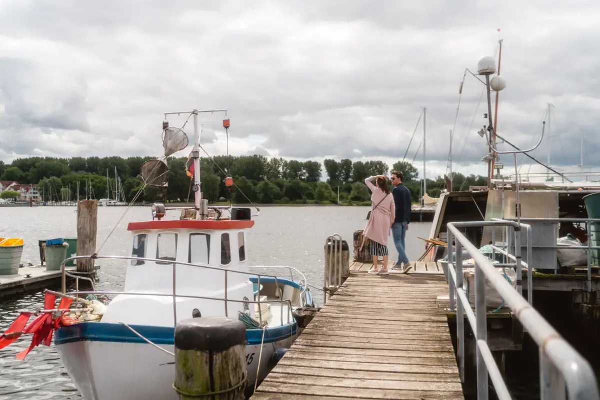 Schlendern in Travemünde Ein Mann und eine Frau stehen auf einem Steg neben einem Boot im Travemünder Hafen.