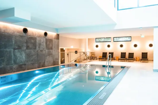 Innenpool mit Treppe und Stühlen.