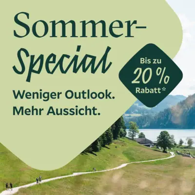 Grünes Grasfeld mit Bäumen und einem See.