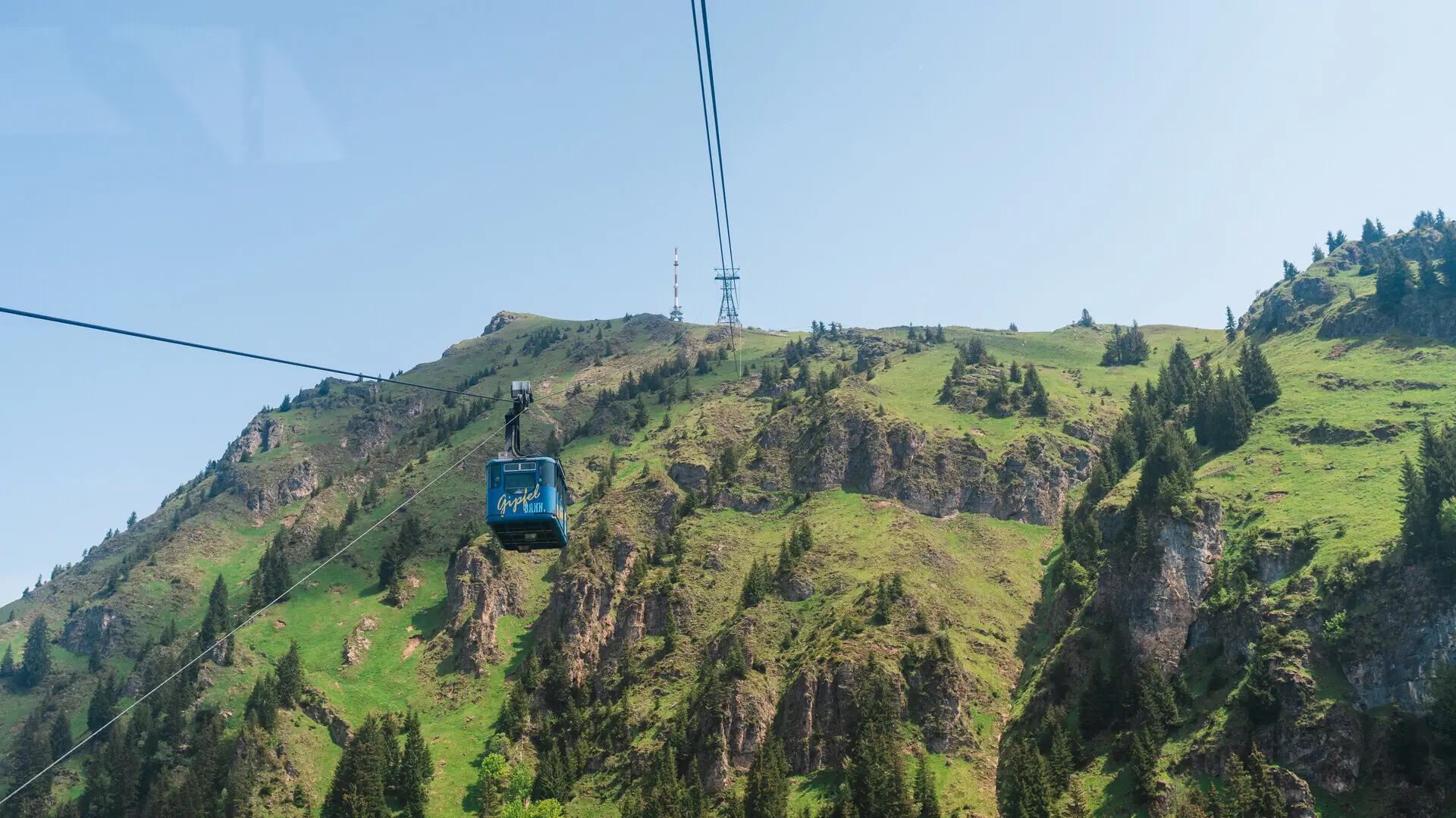 Seilbahn fährt einen Berg hinauf vor blauem Himmel.