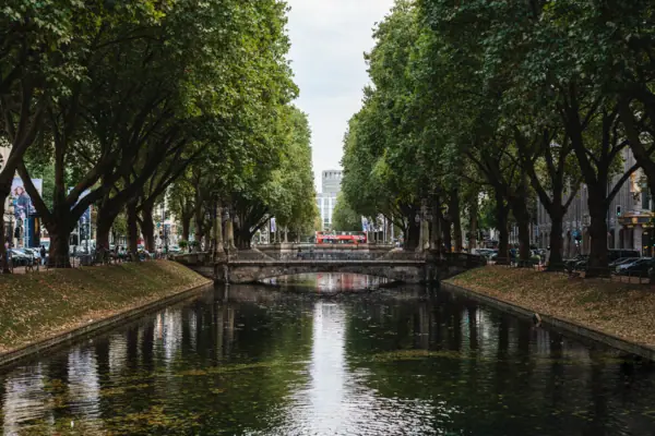Königsallee Düsseldorf Ein Fluss mit Bäumen und einer Brücke darüber.