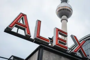 HENRI Berlin Alexanderplatz Ein Schild mit einem hohen Turm im Hintergrund.