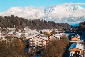 HENRI Kitzbühel Drohnenansicht Ein Bergdorf mit schneebedeckten Bergen im Hintergrund.