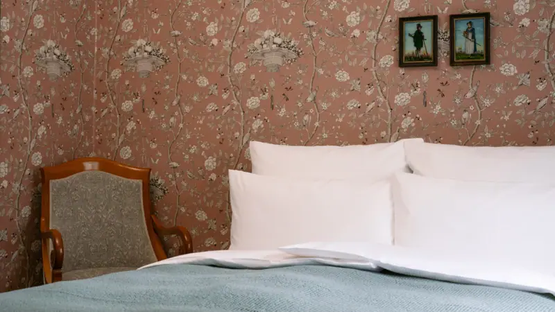 Ein Bett mit Kissen und einem Stuhl in einem Zimmer.