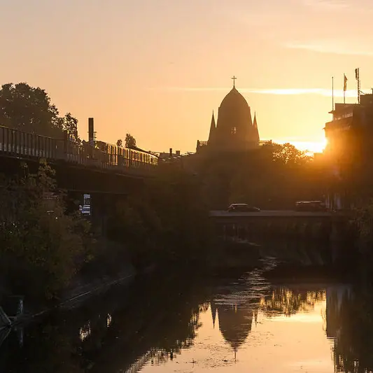 Spree in Berlin bei Abendstimmung Brücke über einen Fluss mit einem Gebäude im Hintergrund bei Sonnenuntergang.