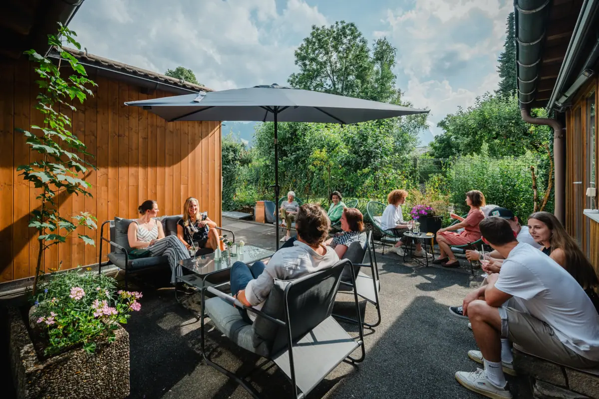 Eine Gruppe von Menschen sitzt draußen auf einer Terrasse.